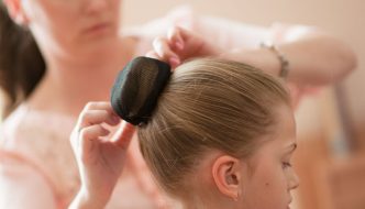 woman helping with young ballerinas hair