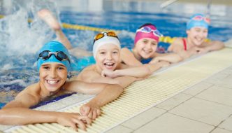 swim class students smiling by edge of pool