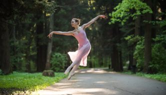 ballet dancer jumping on road through wooded forest