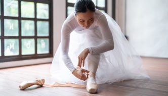 teen ballerina girl student putting on ballet shoes