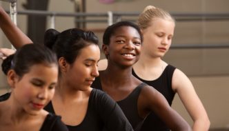 four happy teen ballerinas practicing in the dance studio
