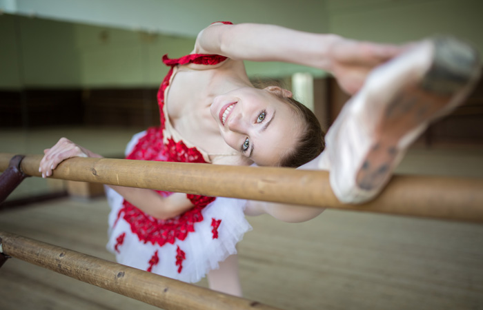 teen ballerina in red and white dress stretching