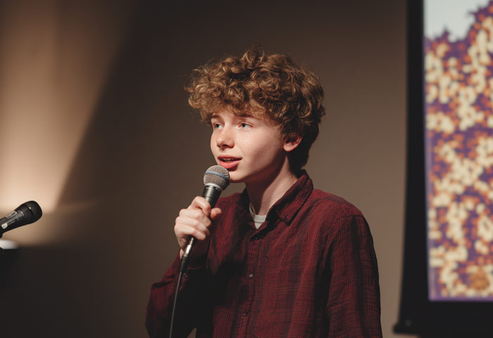 young teen boy on stage doing standup comedy